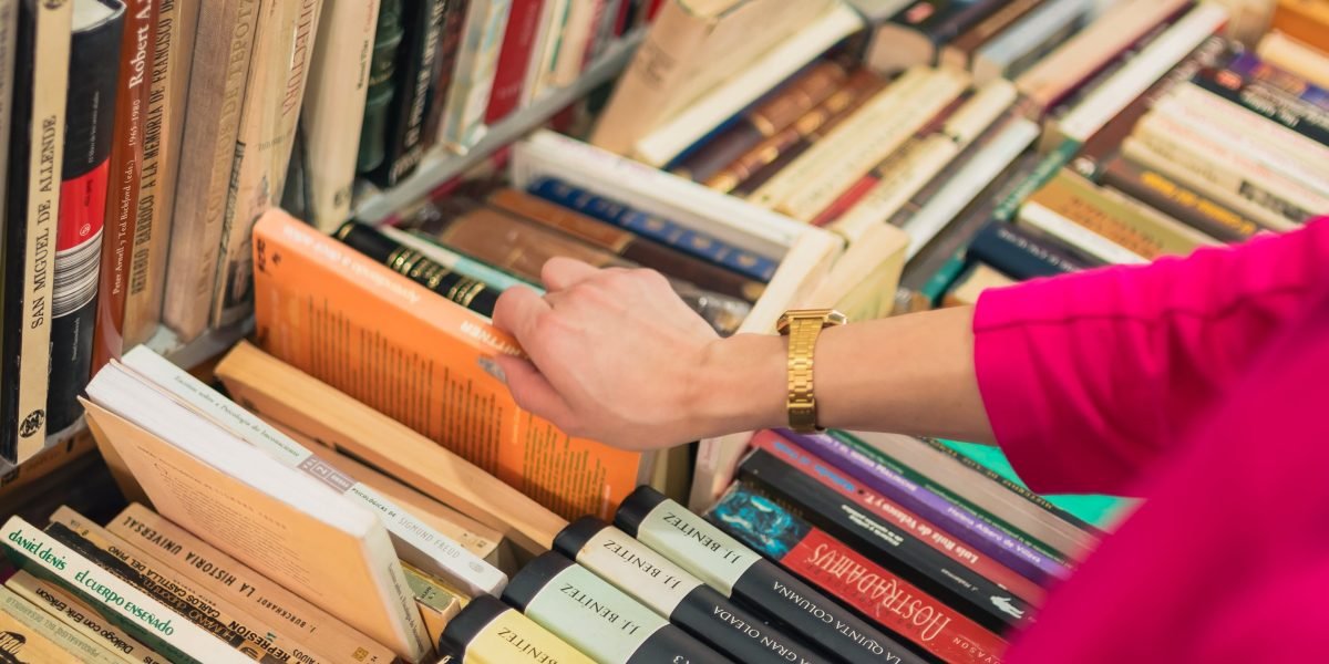 A person looking at a vast selection of books, contemplating which one to choose.