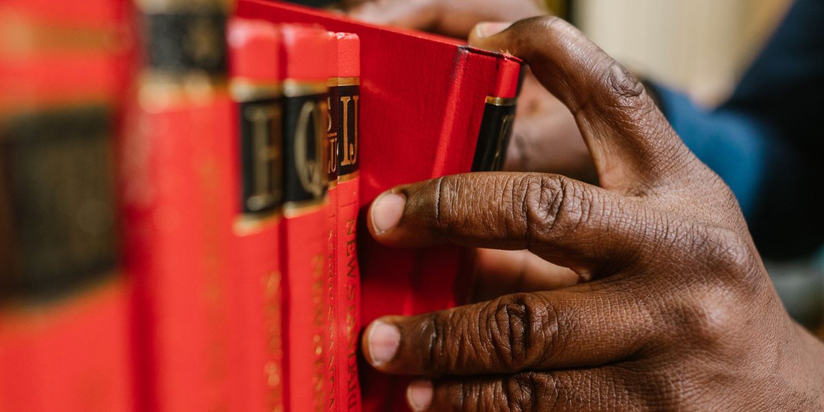 A thoughtful reader browses a bookshelf, carefully considering which humorous book series to pick next.