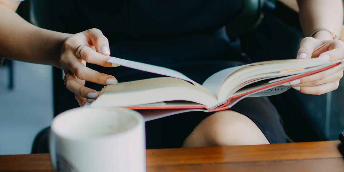 A person comfortably engrossed in a book within a cozy reading nook, embodying the pleasant atmosphere of a great bookstore.