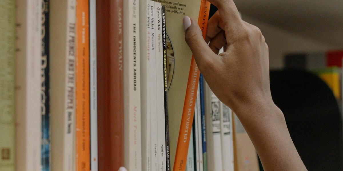 A reader meticulously organizing their book collection, perhaps a full series.